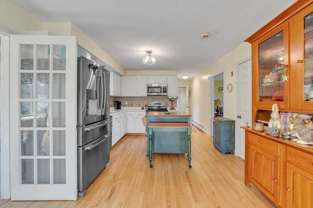 kitchen with light wood-style floors, light countertops, stainless steel appliances, backsplash, and glass insert cabinets