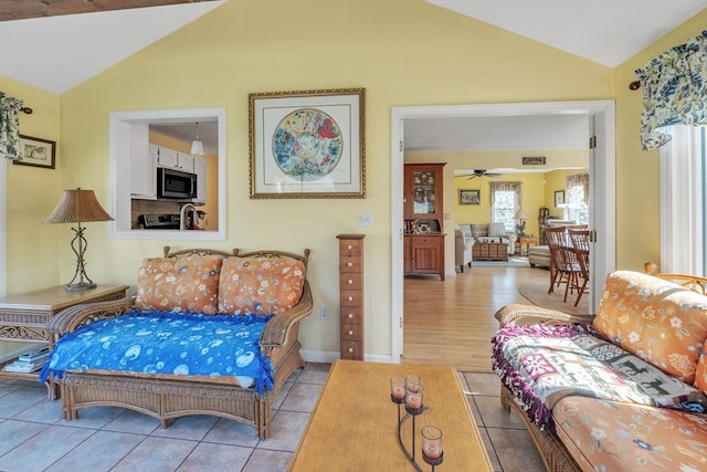living room with tile patterned floors, vaulted ceiling, and ceiling fan