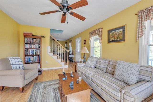 living room with stairway, baseboards, ceiling fan, and wood finished floors