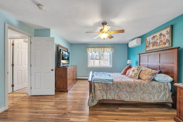 bedroom with baseboard heating, ceiling fan, a wall mounted AC, and wood finished floors
