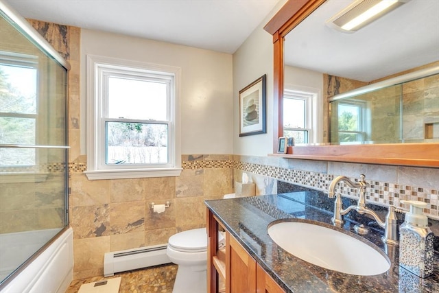 full bath with vanity, toilet, tile walls, baseboard heating, and enclosed tub / shower combo