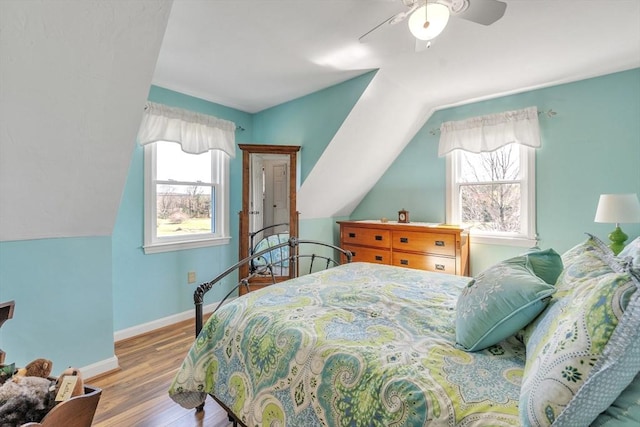 bedroom with baseboards, vaulted ceiling, multiple windows, and wood finished floors