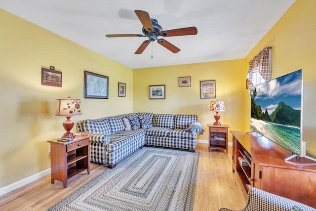living room featuring baseboards, a ceiling fan, and wood finished floors