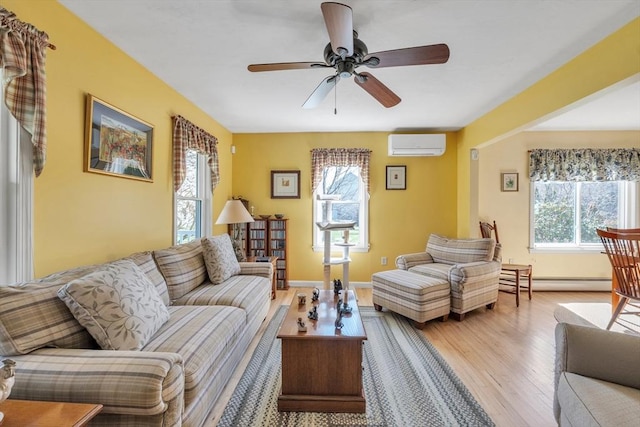 living room with ceiling fan, light wood-type flooring, a healthy amount of sunlight, and a wall mounted air conditioner