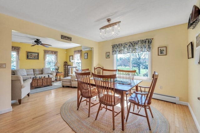 dining space with a wall mounted air conditioner, ceiling fan with notable chandelier, baseboards, light wood-type flooring, and a baseboard radiator