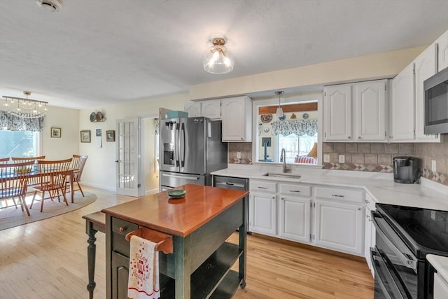 kitchen with a sink, appliances with stainless steel finishes, a healthy amount of sunlight, and tasteful backsplash