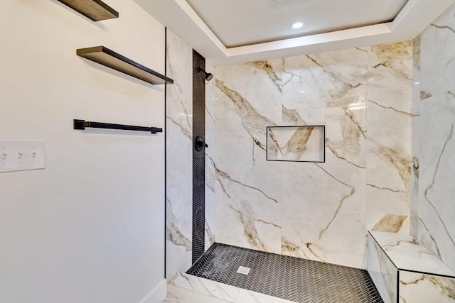 bathroom with a tray ceiling and tiled shower