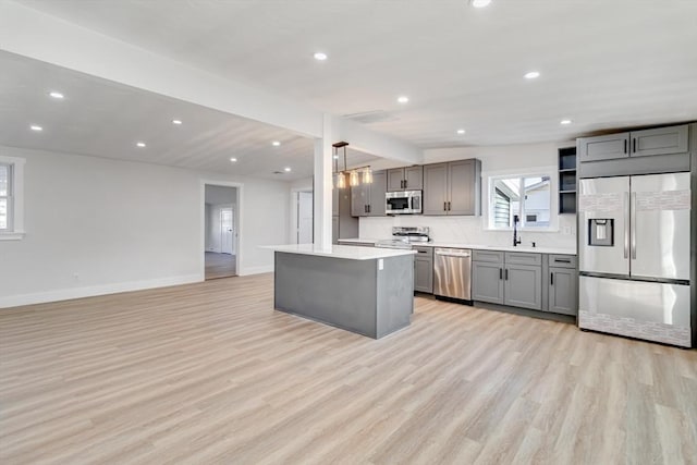 kitchen with lofted ceiling, hanging light fixtures, gray cabinets, a kitchen island, and stainless steel appliances