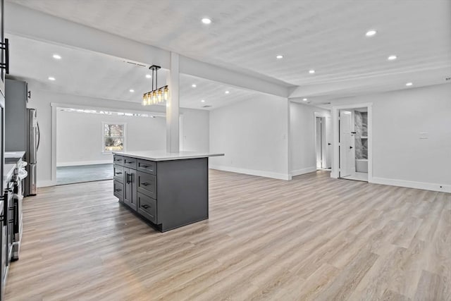 kitchen with light wood-type flooring, stainless steel appliances, decorative light fixtures, gray cabinets, and a kitchen island