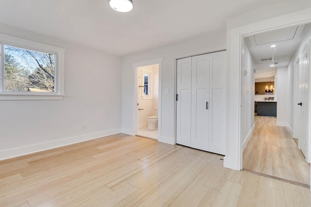 unfurnished bedroom with connected bathroom, a closet, and light wood-type flooring