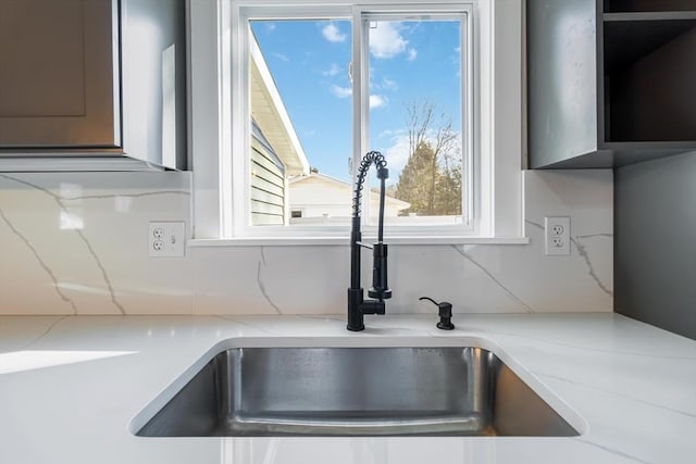 details with decorative backsplash, light stone countertops, and sink