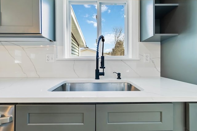 kitchen featuring backsplash, gray cabinets, light stone countertops, and sink