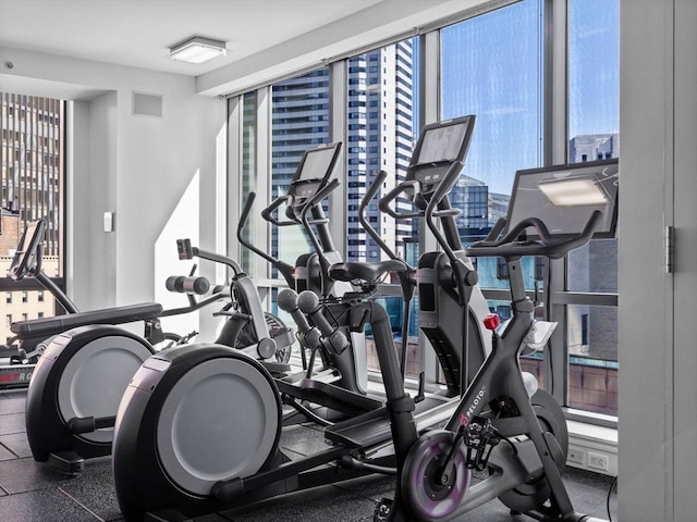 workout area with a wealth of natural light, visible vents, and a wall of windows