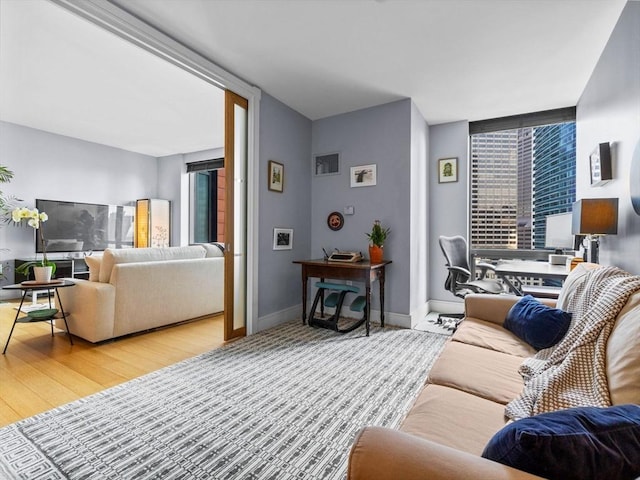 living area with wood finished floors, baseboards, and expansive windows