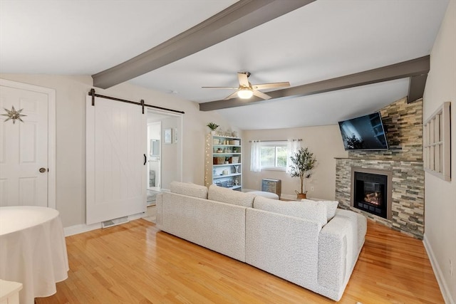 558 Amesbury Rd, Haverhill, MA 01830 - living room with a barn door, light wood finished floors, a ceiling fan, and a fireplace