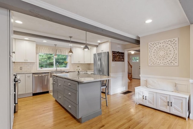 558 Amesbury Rd, Haverhill, MA 01830 - kitchen with stainless steel appliances, gray cabinets, a breakfast bar, plenty of natural light, and a wainscoted wall