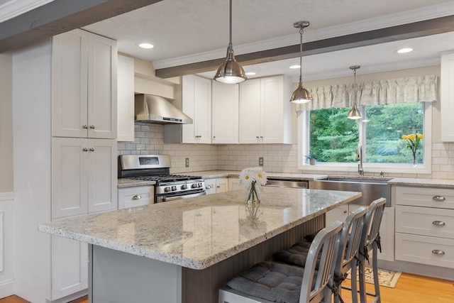 558 Amesbury Rd, Haverhill, MA 01830 - kitchen featuring gas range, wall chimney exhaust hood, a breakfast bar area, ornamental molding, and light stone countertops