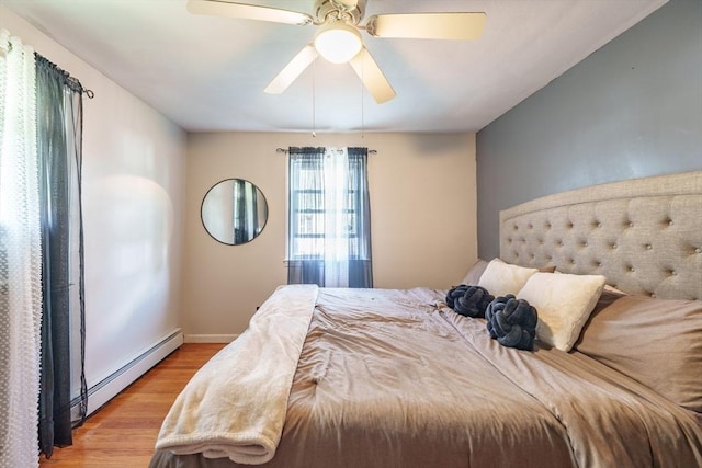bedroom featuring light wood finished floors, baseboard heating, baseboards, and a ceiling fan