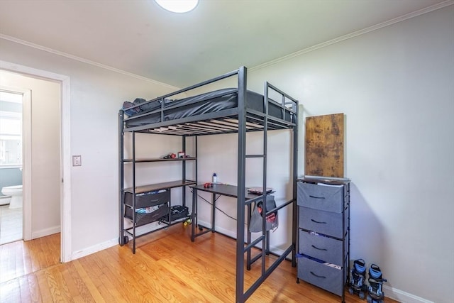 bedroom with wood finished floors, baseboards, and ornamental molding