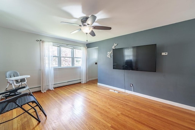 living area with baseboards, a ceiling fan, wood finished floors, and a baseboard radiator