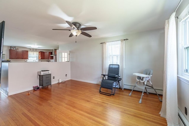 sitting room featuring ceiling fan, a healthy amount of sunlight, light wood-style floors, and a baseboard radiator