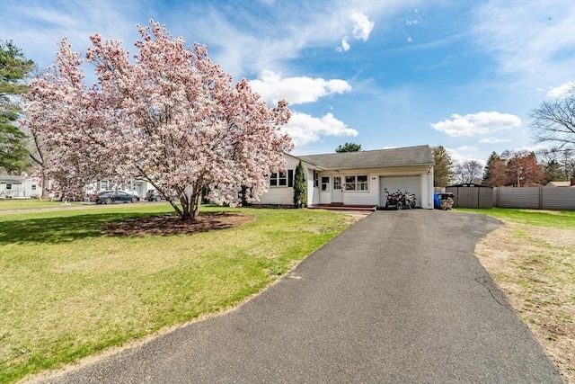 view of front facade with aphalt driveway, fence, a front yard, and a garage
