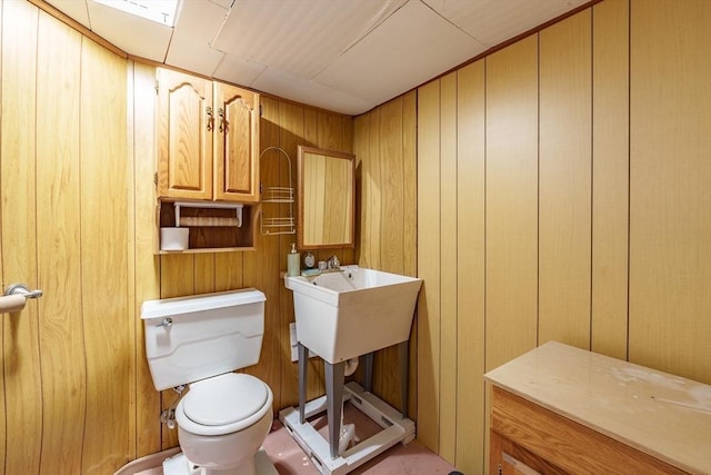 bathroom featuring wooden walls and toilet