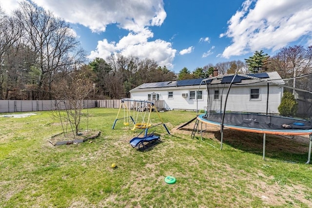 view of yard with a trampoline, a playground, and fence