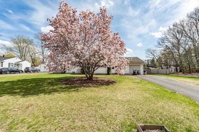 view of front of house with an attached garage, driveway, a front lawn, and fence