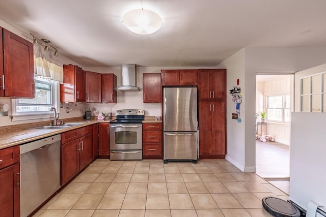kitchen with baseboard heating, dark brown cabinets, a sink, wall chimney exhaust hood, and appliances with stainless steel finishes