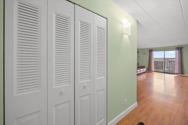 hallway with light hardwood / wood-style floors and a textured ceiling