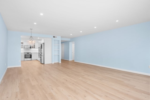 unfurnished living room featuring light wood-type flooring and a chandelier