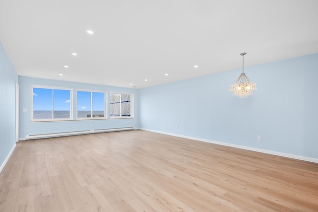 unfurnished living room with light hardwood / wood-style flooring, a notable chandelier, and a baseboard heating unit