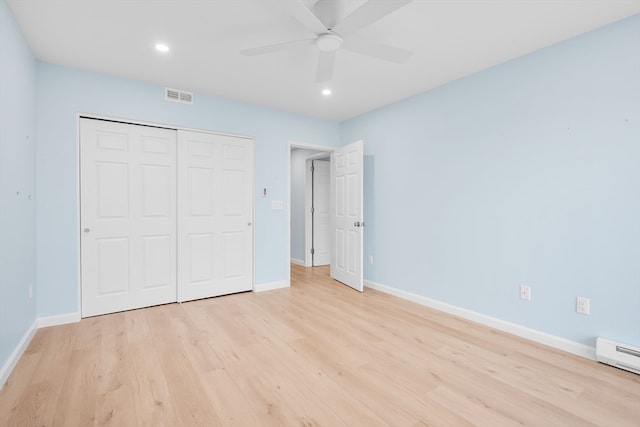 unfurnished bedroom with a closet, light hardwood / wood-style flooring, ceiling fan, and a baseboard heating unit