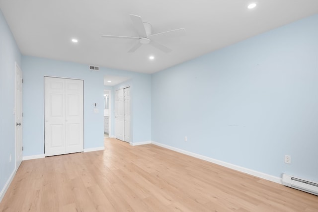 unfurnished bedroom featuring multiple closets, ceiling fan, a baseboard radiator, and light wood-type flooring