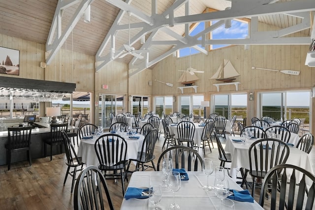 dining space with wood-type flooring, high vaulted ceiling, beam ceiling, and wood walls