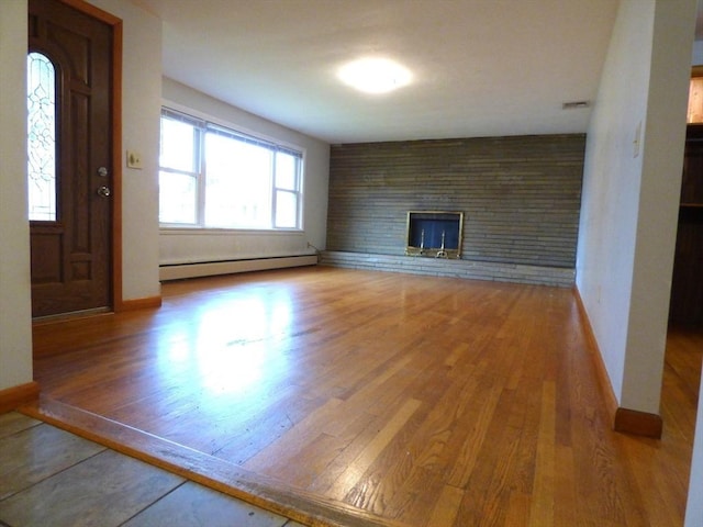 25 Williams St, Ludlow, MA 01056 - unfurnished living room featuring baseboard heating, wood finished floors, a fireplace, and baseboards