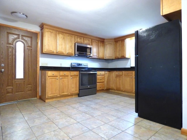 25 Williams St, Ludlow, MA 01056 - kitchen featuring appliances with stainless steel finishes, dark countertops, light tile patterned floors, and brown cabinetry
