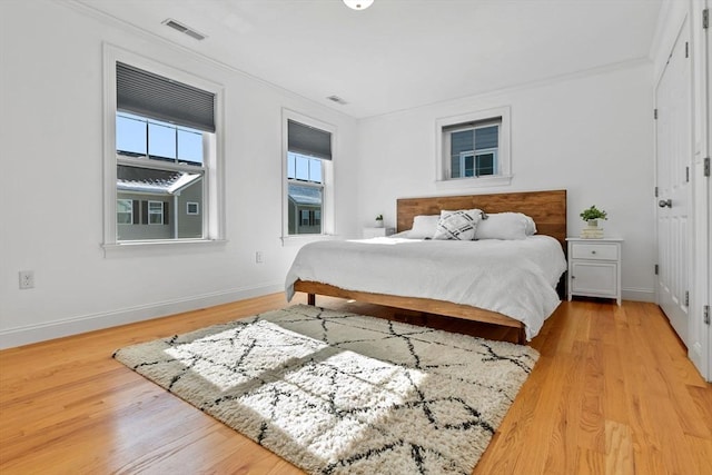 bedroom with ornamental molding and light hardwood / wood-style floors