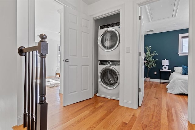 clothes washing area featuring stacked washer / dryer and light hardwood / wood-style flooring