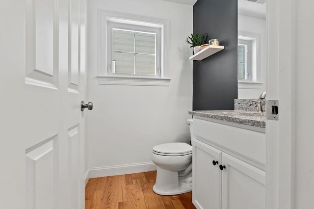 bathroom featuring wood-type flooring, vanity, and toilet