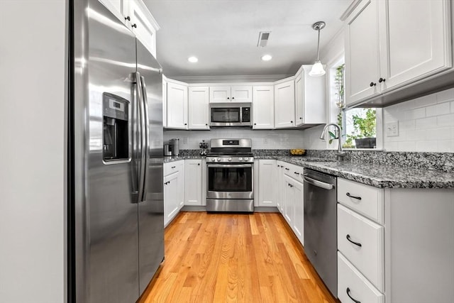 kitchen featuring white cabinetry, stainless steel appliances, decorative light fixtures, sink, and decorative backsplash