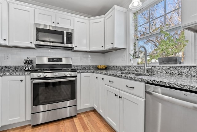 kitchen featuring white cabinetry, stainless steel appliances, light hardwood / wood-style floors, sink, and light stone counters