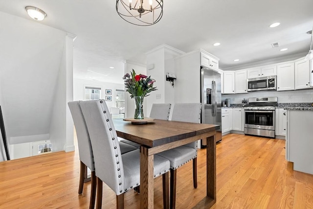 dining space with light wood-type flooring and an inviting chandelier