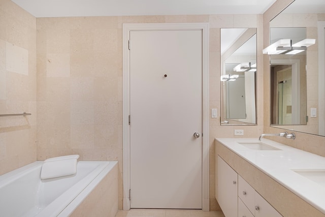 bathroom featuring tile patterned floors, vanity, a bathing tub, and tile walls