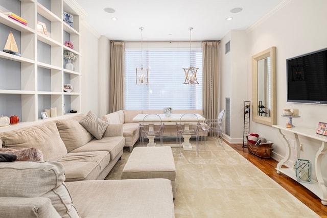 living room featuring ornamental molding, wood-type flooring, and an inviting chandelier