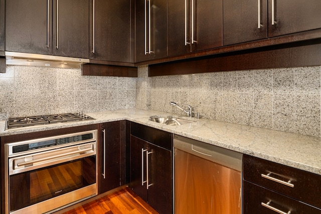 kitchen with dark wood-type flooring, ventilation hood, tasteful backsplash, light stone counters, and stainless steel appliances