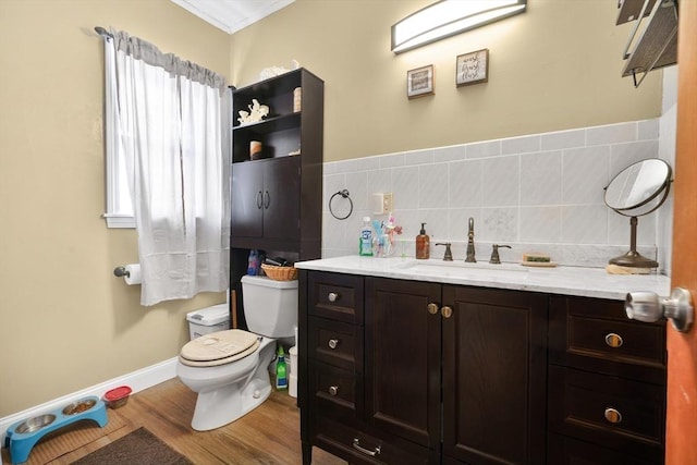 bathroom featuring tile walls, hardwood / wood-style flooring, vanity, toilet, and crown molding