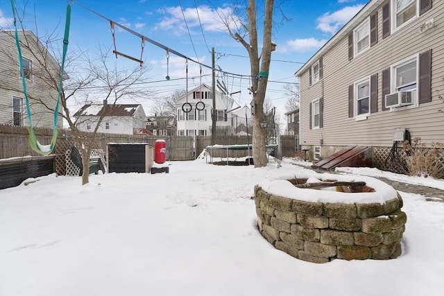 snowy yard featuring a trampoline, cooling unit, and a fire pit