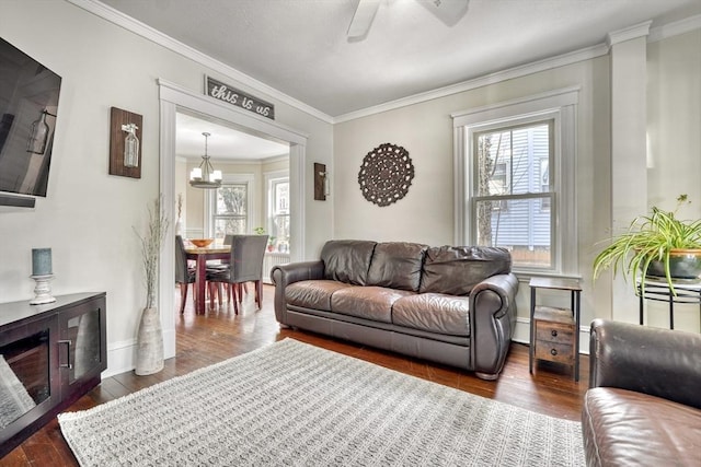 living area featuring crown molding, plenty of natural light, dark wood-style flooring, a chandelier, and ceiling fan